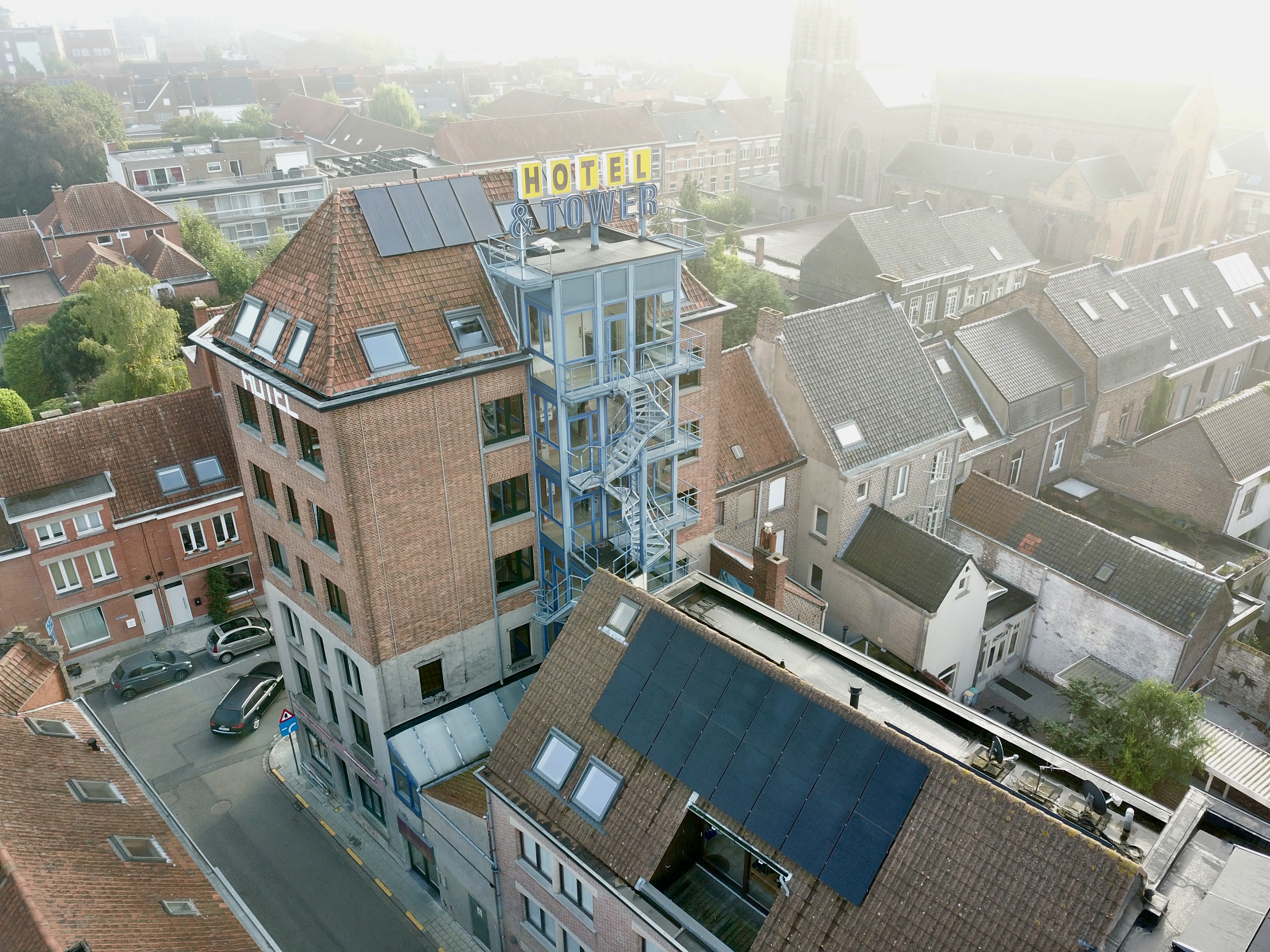 Luchtfoto van hotel en toren met zonnepanelen en de zonneboilers op het dak.